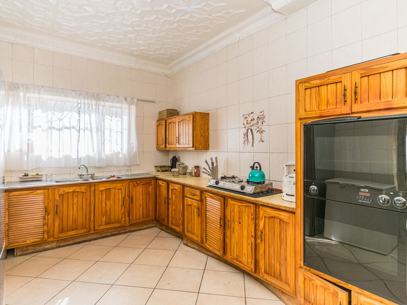 A functional kitchen featuring wooden cabinetry, a built-in oven, gas hob, and tiled finishes, offering a classic layout with potential for modern updates.