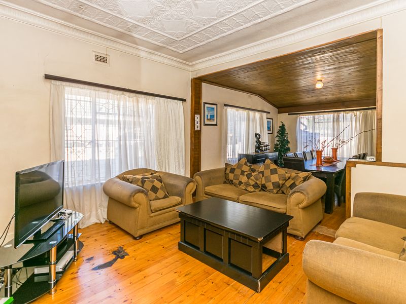 Open-plan living and dining area featuring original timber flooring, a decorative pressed metal ceiling, and a timber-lined ceiling section.