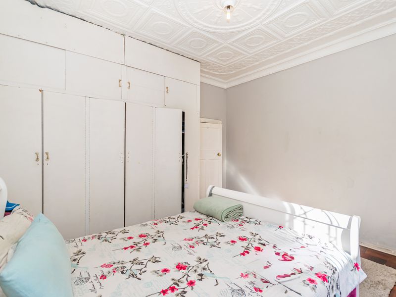 Bedroom featuring classic pressed metal ceilings, hardwood flooring, and extensive built-in storage cabinetry.