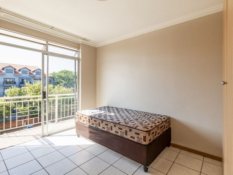 A bedroom featuring tiled flooring, a built-in cupboard, and a sliding glass door that opens onto a private balcony.