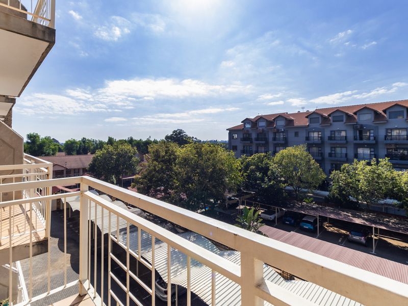 A balcony with a metal balustrade offering an elevated view of the surrounding apartment complex and parking area.