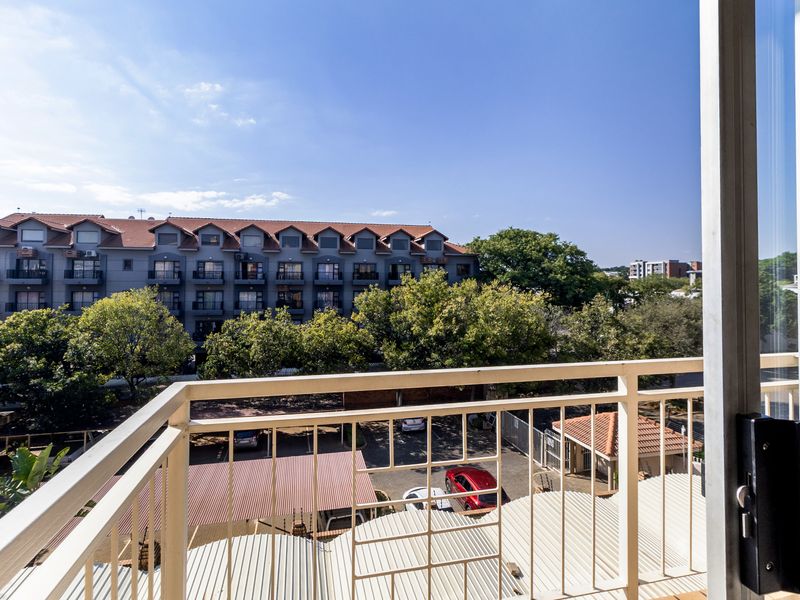 A balcony with a metal balustrade offering an elevated view of the surrounding apartment complex and parking area.