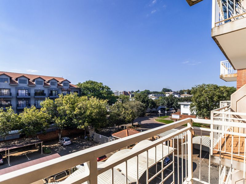 A view from an apartment balcony overlooking the complex parking area and surrounding neighborhood.