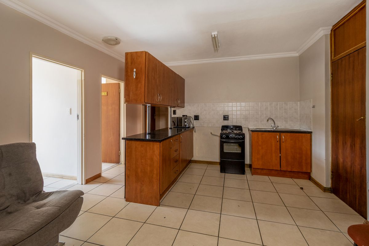 A functional kitchen featuring wooden cabinetry, black granite countertops, a freestanding stove, and tiled flooring, offering a practical layout for daily use.