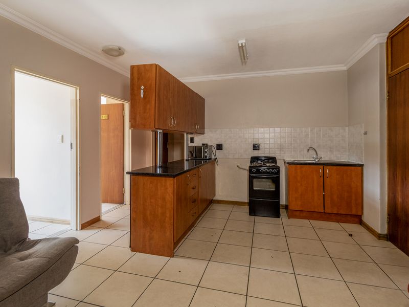 A functional kitchen featuring wooden cabinetry, black granite countertops, a freestanding stove, and tiled flooring, offering a practical layout for daily use.