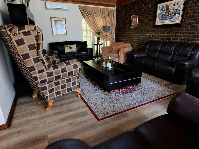 Spacious living room featuring a warm timber ceiling, an exposed brick feature wall, and modern laminate flooring with an installed air conditioning unit.