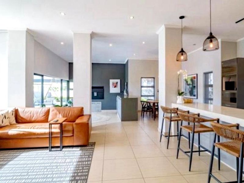 Spacious open-plan living area featuring tiled floors, modern pendant lighting, and a functional breakfast bar connecting to the kitchen space.