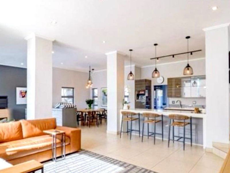 Spacious open-plan living area featuring a modern kitchen with a central island, breakfast bar, and integrated lighting, flowing seamlessly into the dining and lounge space.