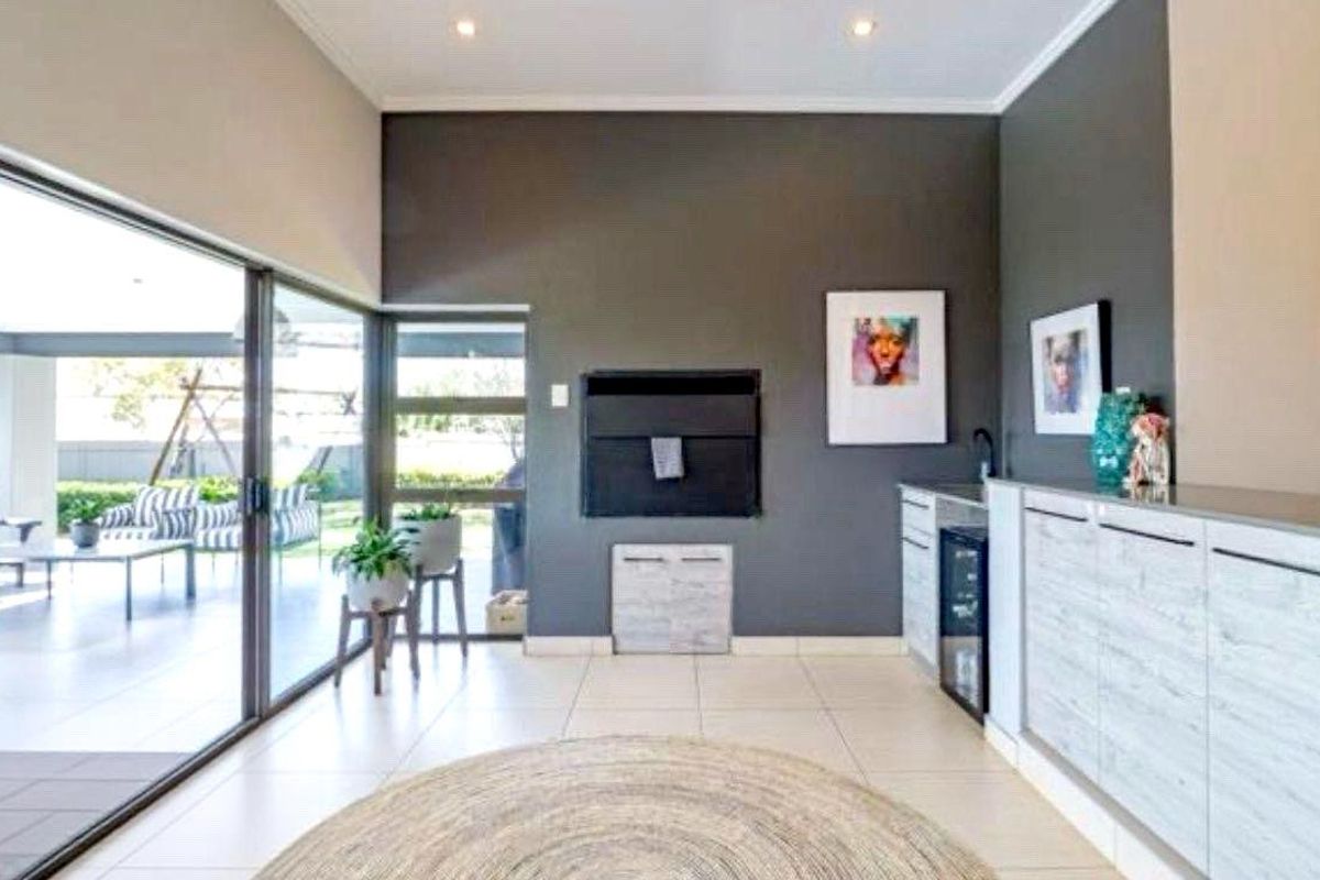 Modern living area featuring a built-in fireplace, sleek cabinetry, and large sliding glass doors that open onto a covered patio.