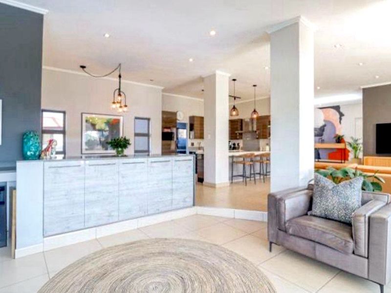 Spacious open-plan living area featuring a modern kitchen with island, tiled flooring, and a fireplace, creating a seamless flow between cooking and lounge spaces.