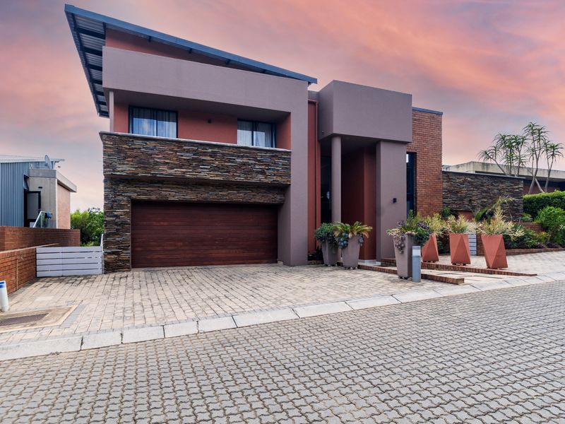 Modern double-story residence featuring a striking combination of stone cladding, brickwork, and a paved driveway with an integrated double garage.