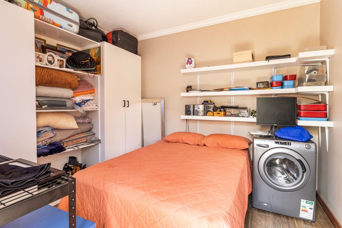 A compact bedroom featuring built-in wardrobe storage and wall-mounted shelving units, providing functional storage space.