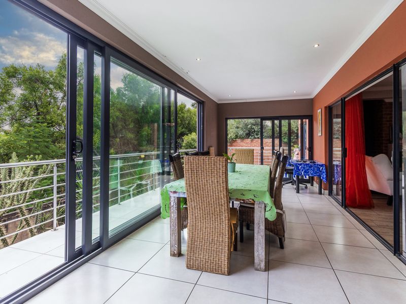 Spacious enclosed patio featuring large sliding glass doors, tiled flooring, and recessed lighting, offering a bright transition space with views of the surrounding greenery.