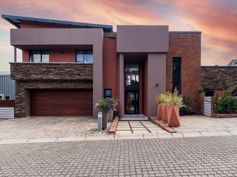 Modern double-story residence featuring a striking combination of brick and stone cladding, a paved driveway, and a prominent covered entrance.