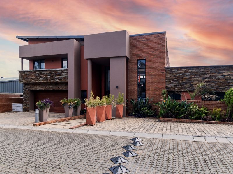 Modern double-story residence featuring a striking combination of brick and stone cladding, a paved driveway, and an integrated garage.