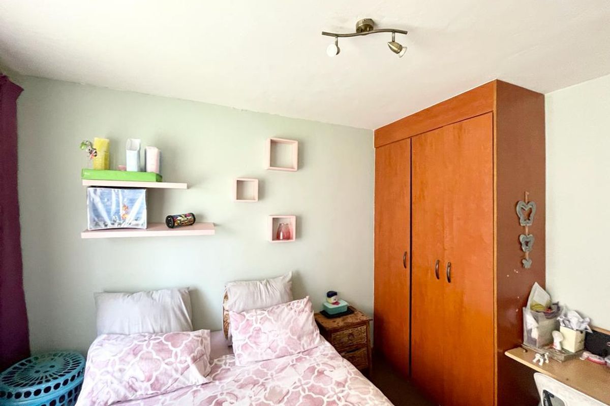 A bedroom featuring a built-in wooden wardrobe and ceiling-mounted spotlight fixture.