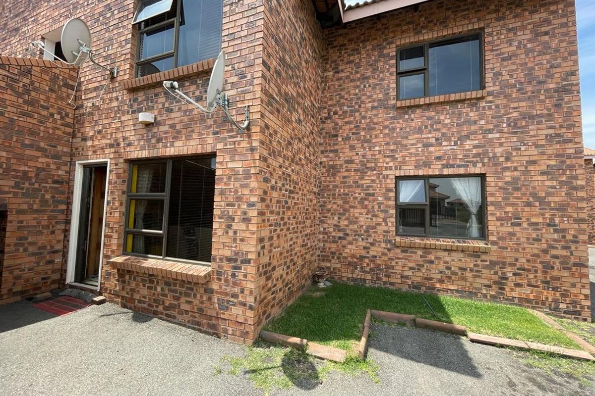 Exterior view of a face-brick apartment building featuring aluminium-framed windows and a paved ground-level entrance area.