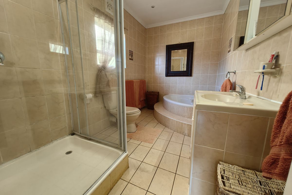 A functional bathroom featuring a glass shower enclosure, a raised corner bathtub, and a tiled vanity with a built-in basin.