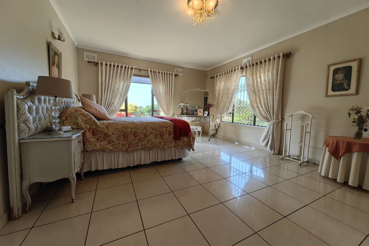 Spacious bedroom featuring large windows with security bars, neutral wall tones, and polished tiled flooring throughout.
