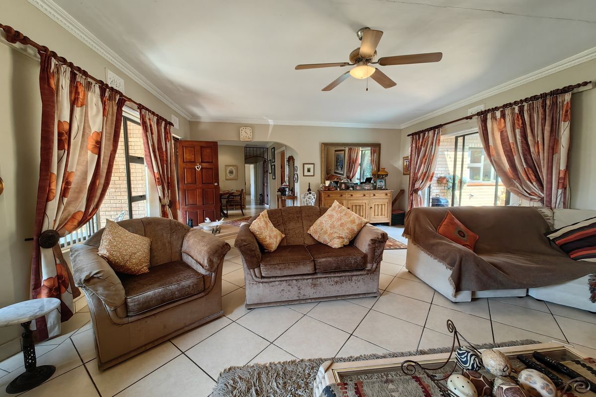 Spacious living room featuring tiled flooring, a ceiling fan, and sliding glass doors providing access to the exterior.