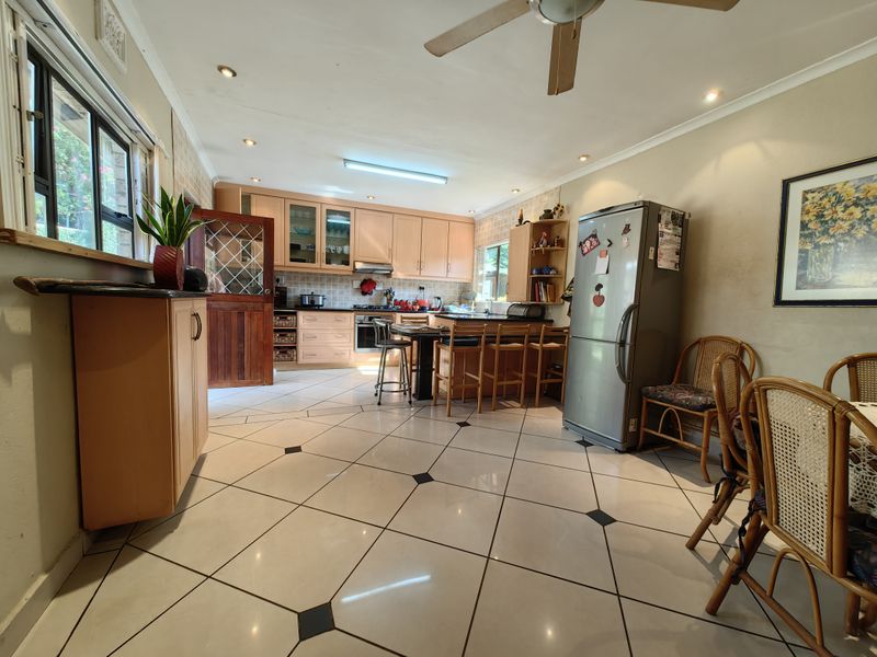 Open-plan kitchen and dining area featuring light wood cabinetry, tiled flooring, and a breakfast counter, offering a functional layout with potential for modernization.