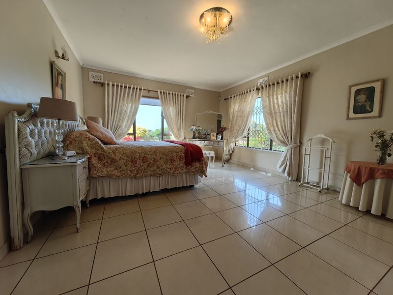 Spacious bedroom featuring large windows with security bars, neutral wall tones, and polished tiled flooring throughout.
