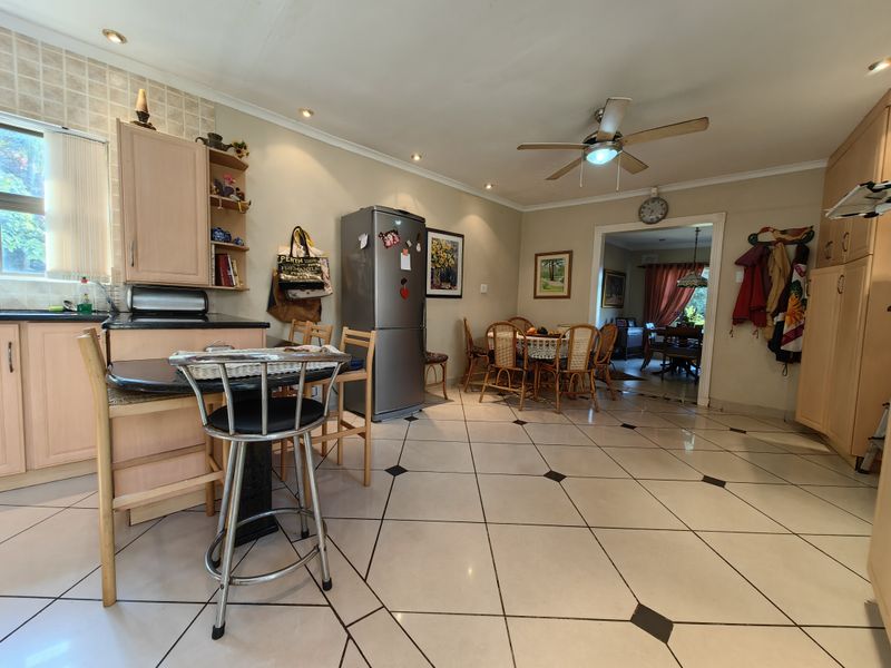 Open plan kitchen and dining area featuring tiled flooring, built-in cabinetry with granite countertops, and a ceiling fan.