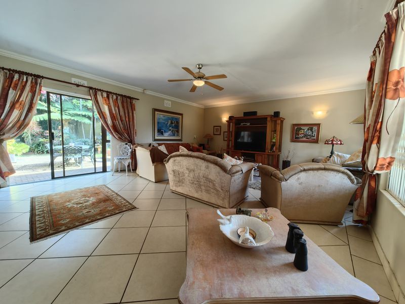 Spacious living room featuring tiled flooring, a ceiling fan, and large sliding glass doors providing direct access to the outdoor patio area.