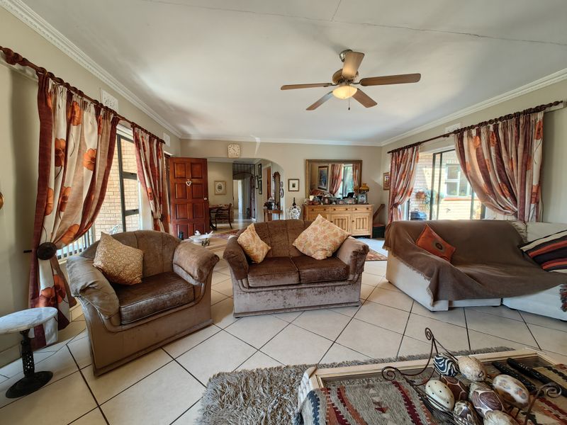 Spacious living room featuring tiled flooring, a ceiling fan, and sliding glass doors providing access to the exterior.