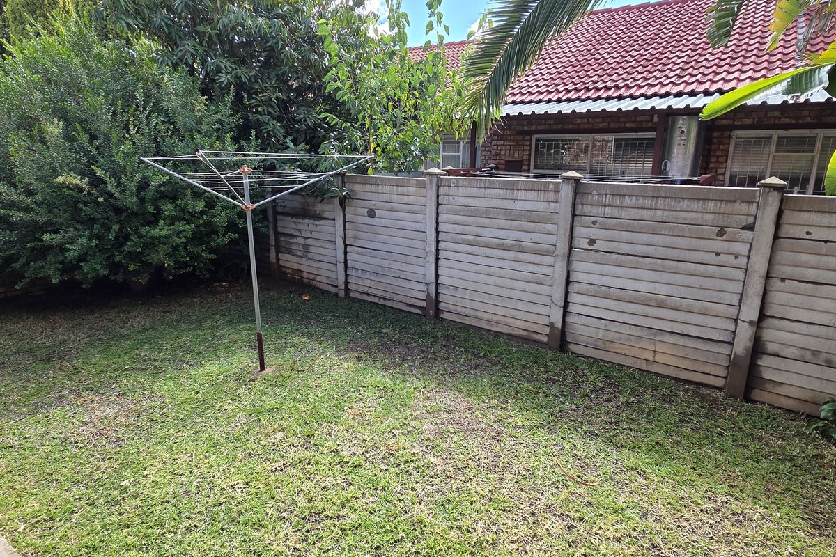 A private rear garden area featuring a lawn, precast concrete boundary walls, and a rotary clothesline.