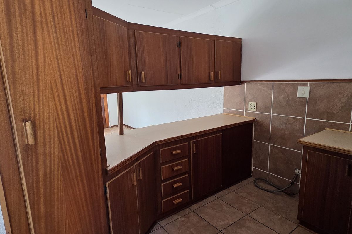 A functional kitchen featuring traditional wooden cabinetry, laminate countertops, and tiled backsplash, offering a clean and practical layout for renovation.