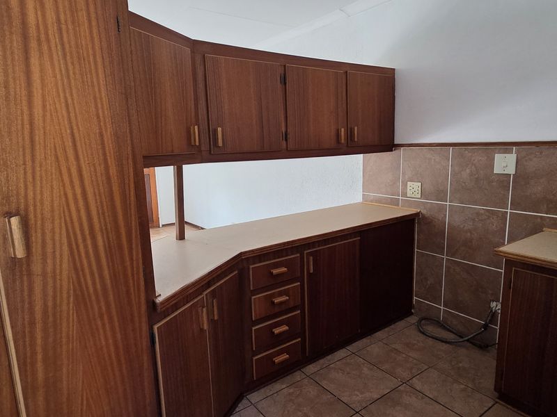 A functional kitchen featuring traditional wooden cabinetry, laminate countertops, and tiled backsplash, offering a clean and practical layout for renovation.