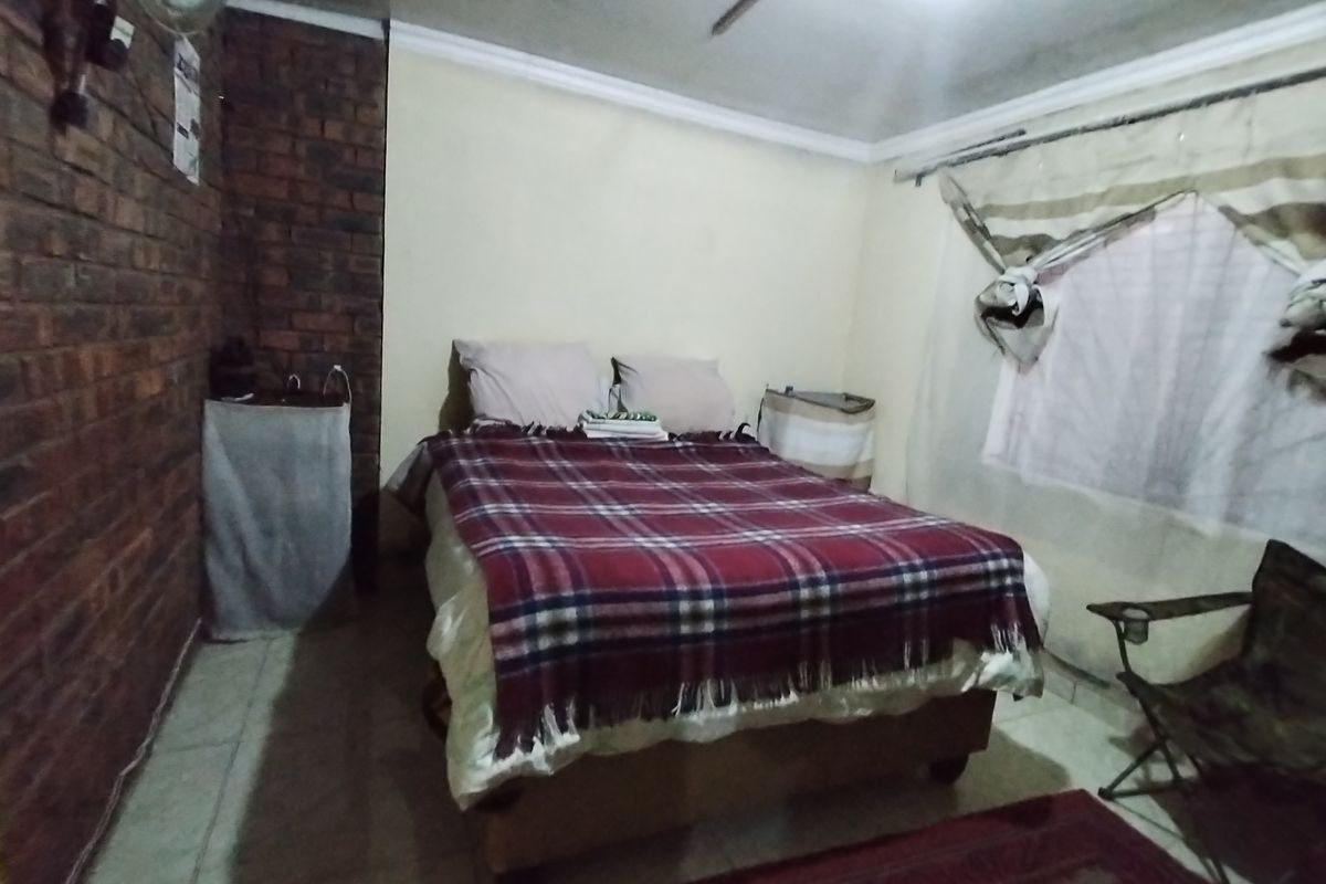 A bedroom featuring an exposed brick feature wall, tiled flooring, and coved ceiling details.
