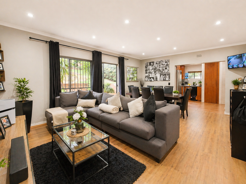 Spacious open-plan living and dining area featuring modern laminate flooring, recessed lighting, and seamless flow to the kitchen and outdoor patio.