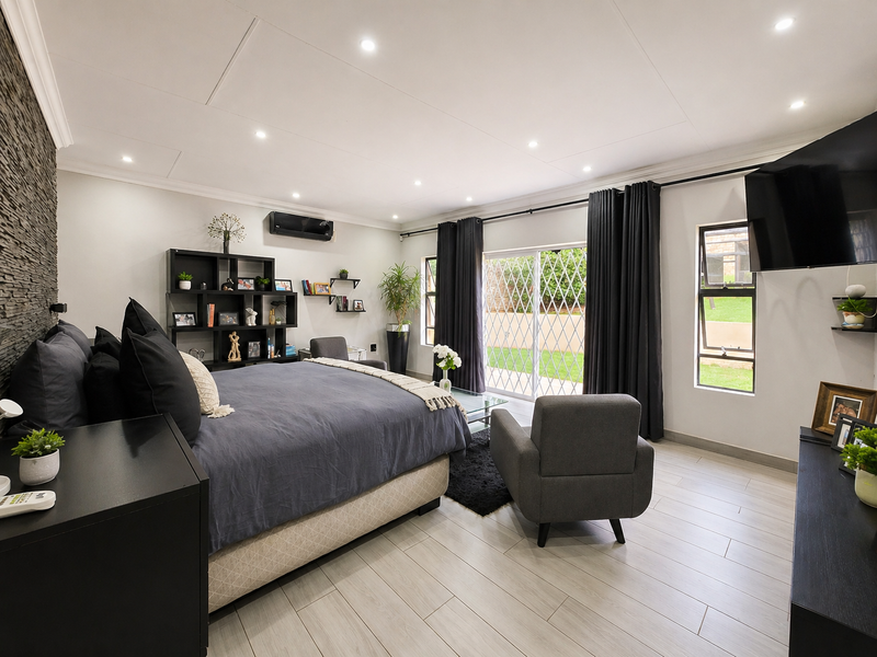 Spacious bedroom featuring a stone accent wall, tiled flooring, recessed lighting, and direct access to the garden through a sliding glass door.