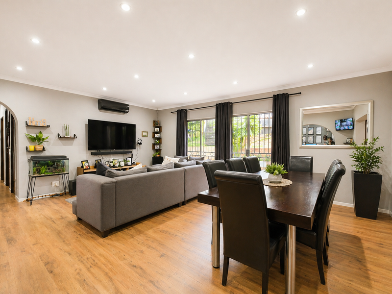 Spacious open-plan living and dining area featuring laminate flooring, recessed downlighting, and sliding glass doors leading to the exterior.
