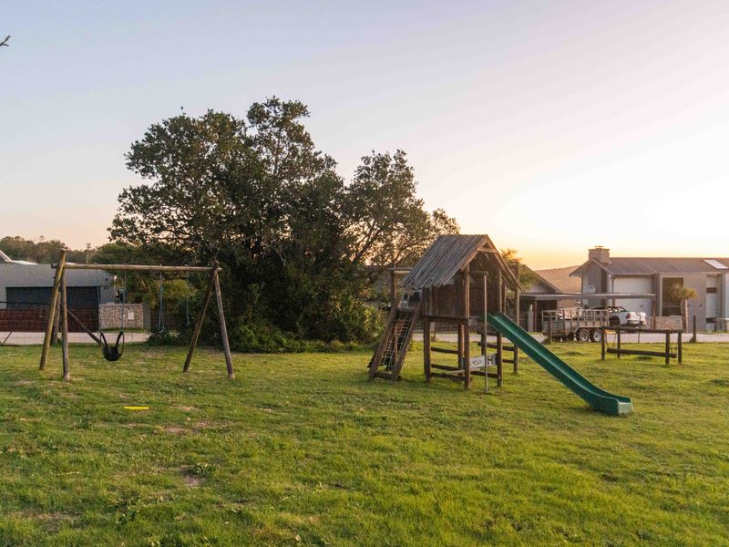 A spacious, well-maintained garden area featuring a large lawn and mature trees, providing an open outdoor space for recreation.