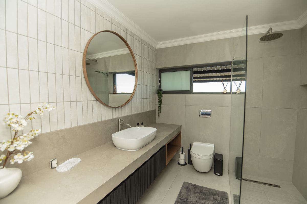 Modern bathroom featuring a floating vanity with vessel sink, walk-in shower with glass screen, wall-hung toilet, and contemporary tiled finishes.