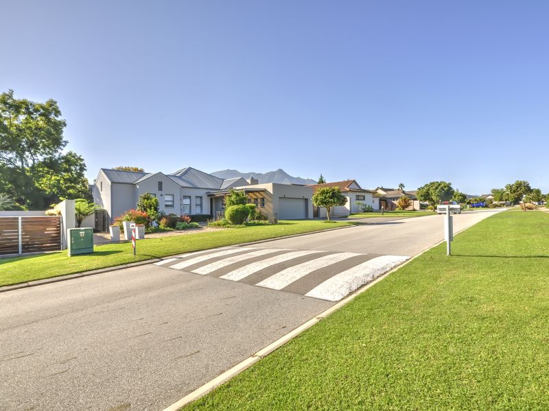 A street-level view of the property showing the front facade, driveway, garage, and well-maintained garden in a quiet residential neighbourhood.