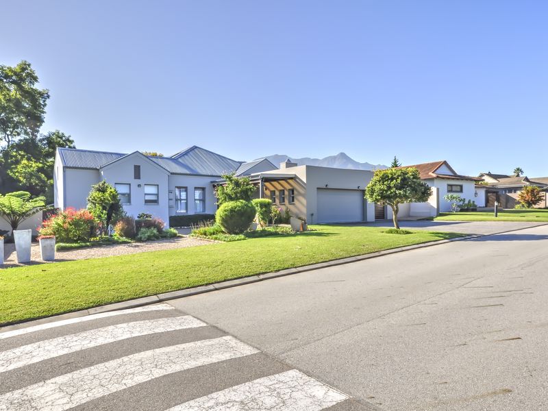 A well-maintained single-story residential property featuring a modern facade, metal roofing, an integrated garage, and a neatly landscaped front garden.