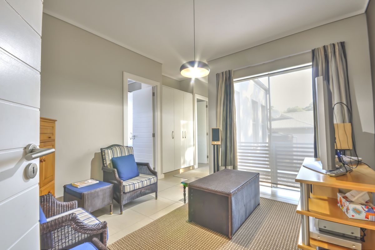 A well-lit bedroom featuring tiled flooring, built-in cupboards, and a sliding glass door providing access to the exterior.