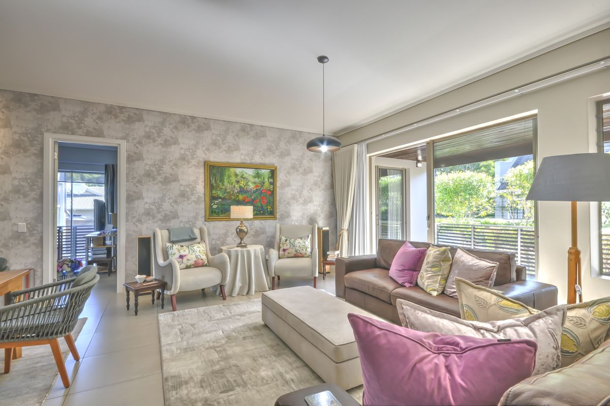 A bright and spacious living room featuring tiled floors, textured feature wall, and large sliding glass doors providing access to the outdoor area.