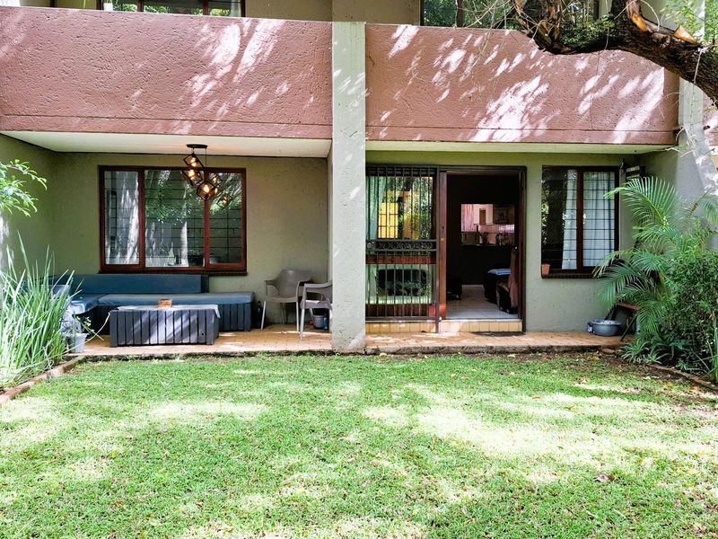 A ground floor apartment featuring a covered patio area with tiled flooring, security gate, and direct access to a private garden space.