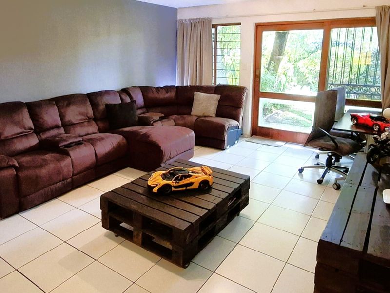 Spacious living room featuring light-colored floor tiles and a large sliding glass door providing direct access to the outdoor area.