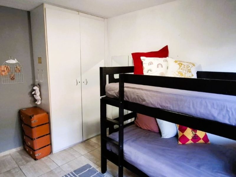 A bedroom featuring tiled flooring and a built-in wardrobe with white doors.