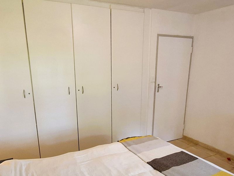 A bedroom featuring built-in cupboards and tiled flooring, offering a functional and neutral space.