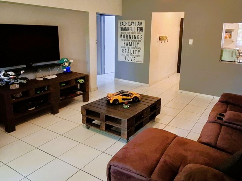 A living room featuring tiled flooring and a convenient pass-through window connecting to the kitchen area.