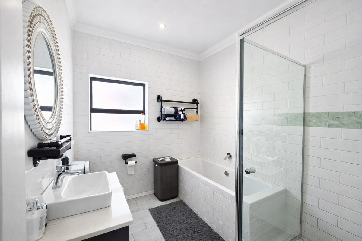 Modern bathroom featuring white subway wall tiles, a glass-enclosed shower, a built-in bathtub, and a contemporary vanity basin with chrome fixtures.