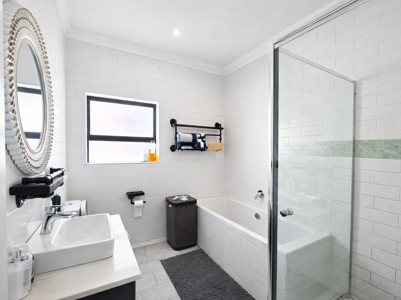 Modern bathroom featuring white subway wall tiles, a glass-enclosed shower, a built-in bathtub, and a contemporary vanity basin with chrome fixtures.