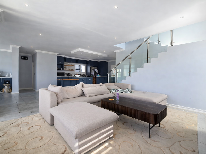Spacious open-plan living area featuring a modern kitchen with dark cabinetry and a contemporary staircase with a glass balustrade.